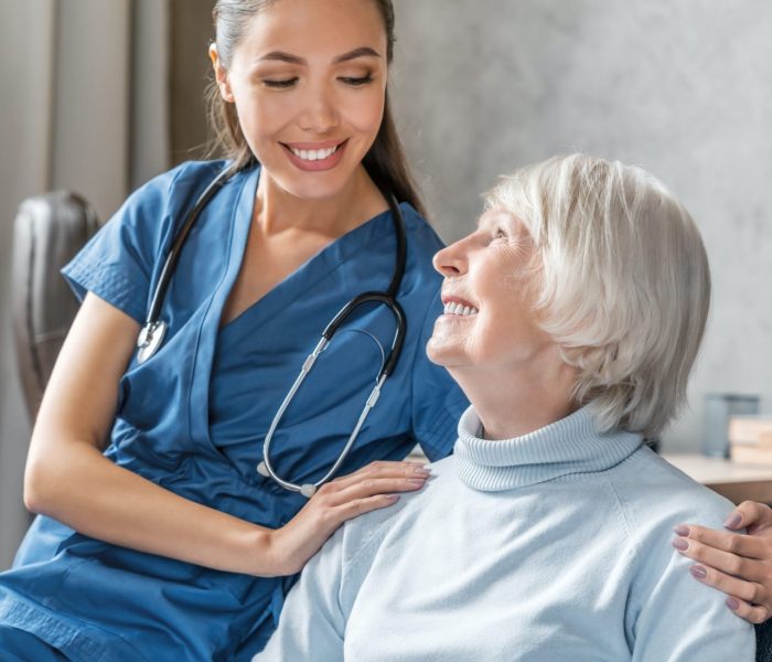vertical-portrait-of-happy-elderly-woman-with-nurse-at-home.jpg